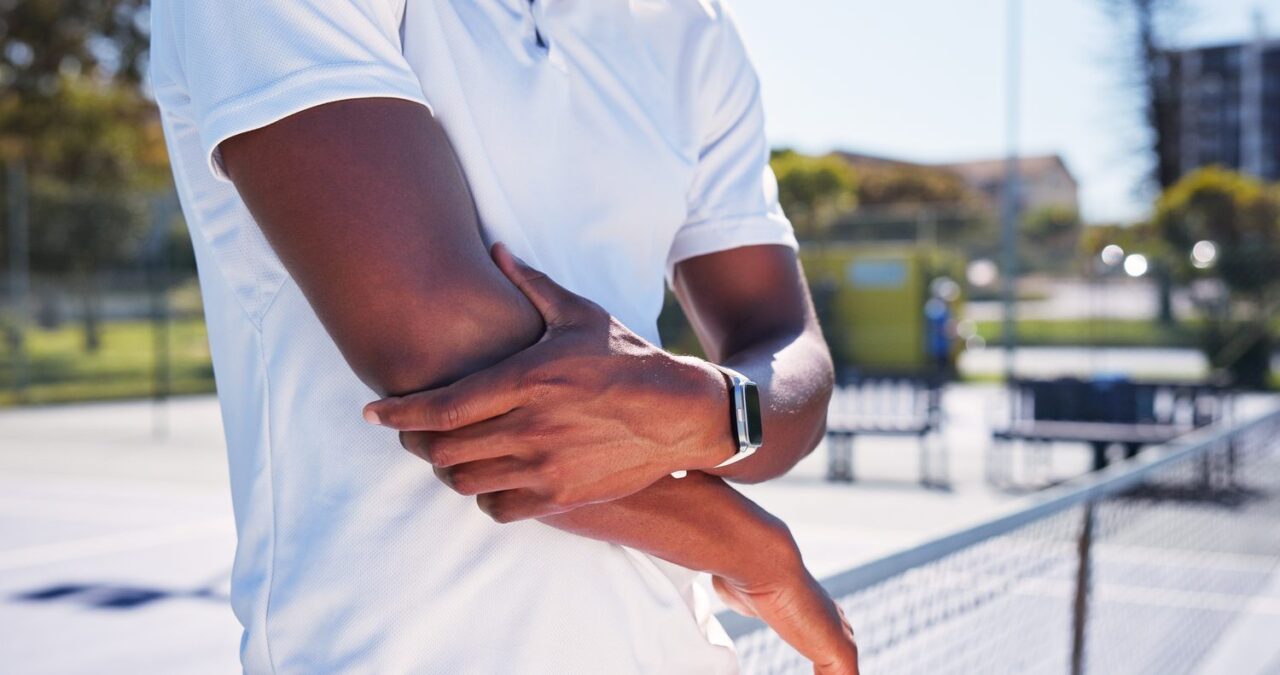 Joueur de tennis se tenant le coude douloureux sur un court.